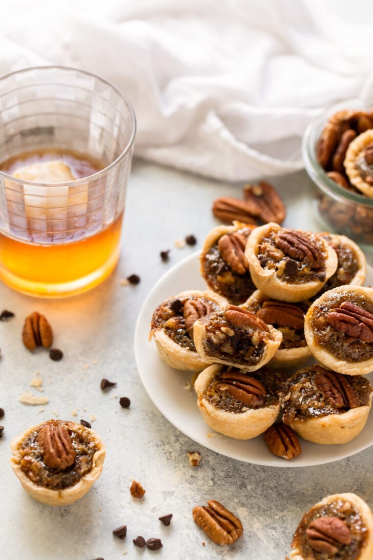 plate of mini derby pies next to glass of bourbon