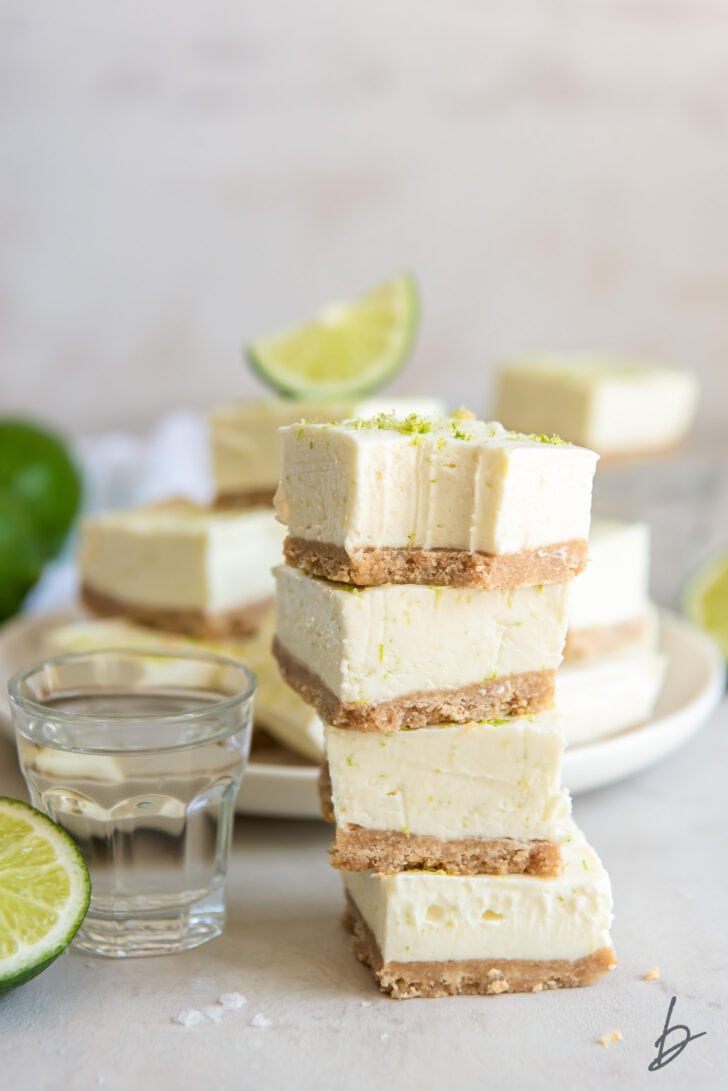 stack of four margarita cheesecake bites next to glass shot of tequila and lime