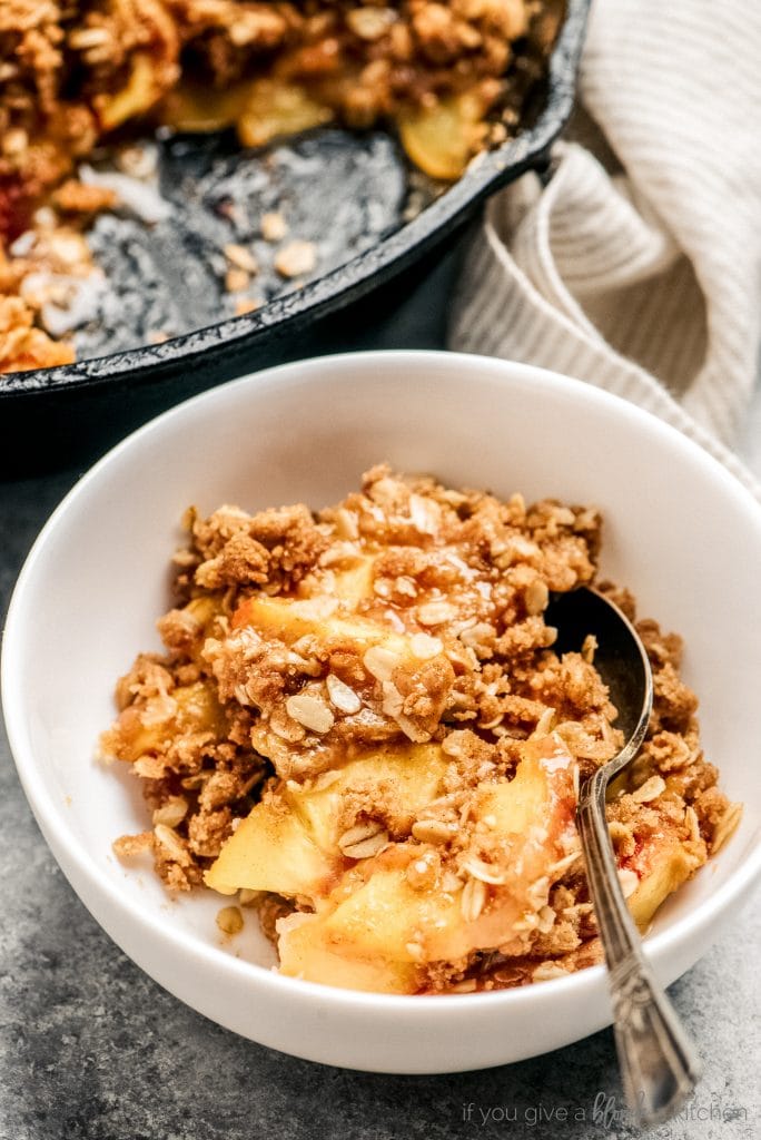 peach crisp serving in bowl with spoon