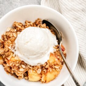 bowl of peach crisp, scoop of vanilla ice cream