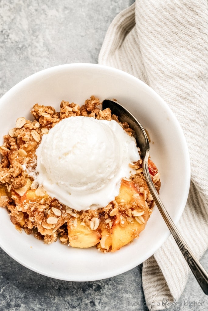 bowl of peach crisp, scoop of vanilla ice cream