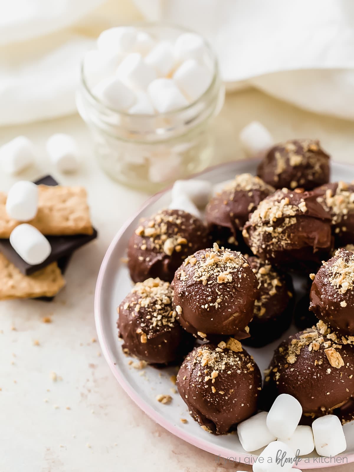 S'mores truffles are no-bake summertime treats made with crushed graham crackers, marshmallow fluff, melted chocolate and a mini marshmallow hiding inside! | Recipe on www.ifyougiveablondeakitchen.com