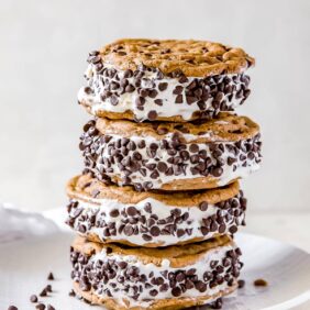 stack of four chocolate chip cookie ice cream sandwiches on white plate.