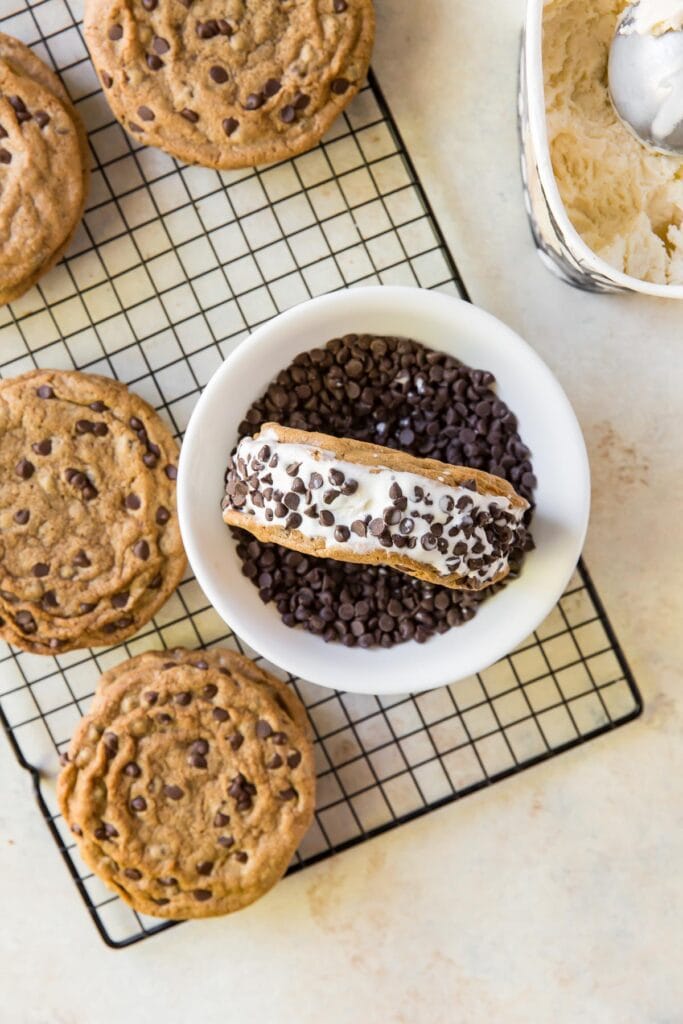 chocolate chip cookie ice cream sandwich on its side in bowl of mini chocolate chips
