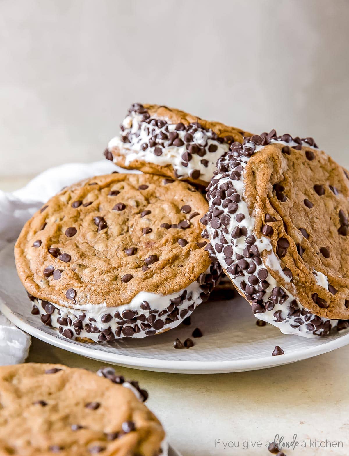 plate of three cookie ice cream sandwiches with mini chips on the edges.