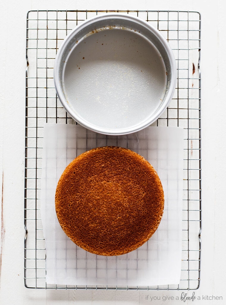 magic cake pan release round cake and cake pan on wire cooling rack. White wood background