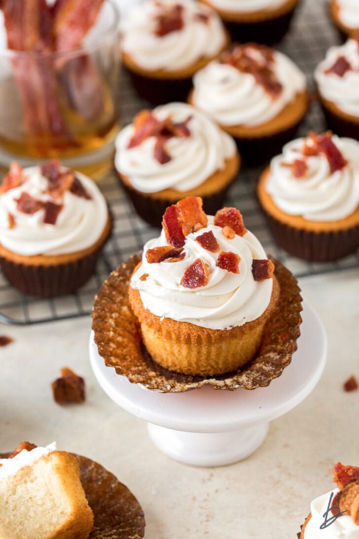 bacon maple bourbon cupcake on an open paper cupcake liner on mini white dessert stand