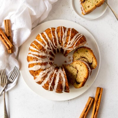 cinnamon zucchini bundt cake on white plate with two slices cut