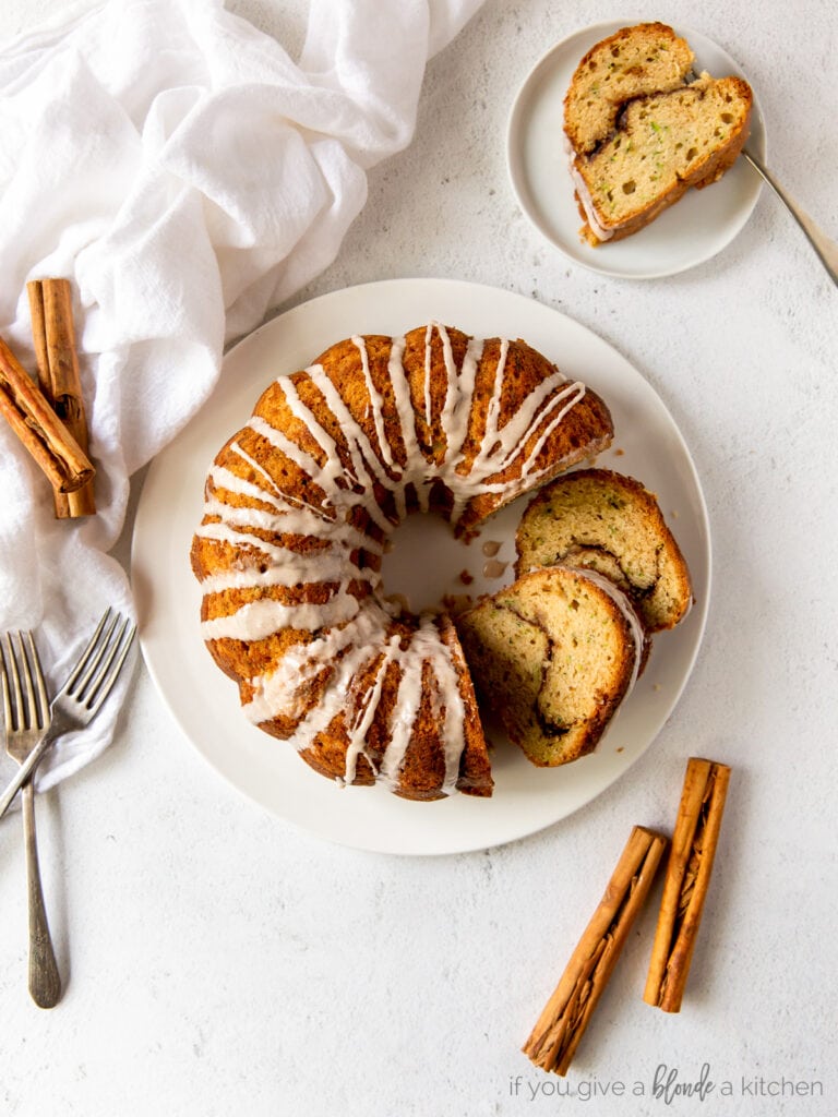 cinnamon zucchini bundt cake on white plate with two slices cut