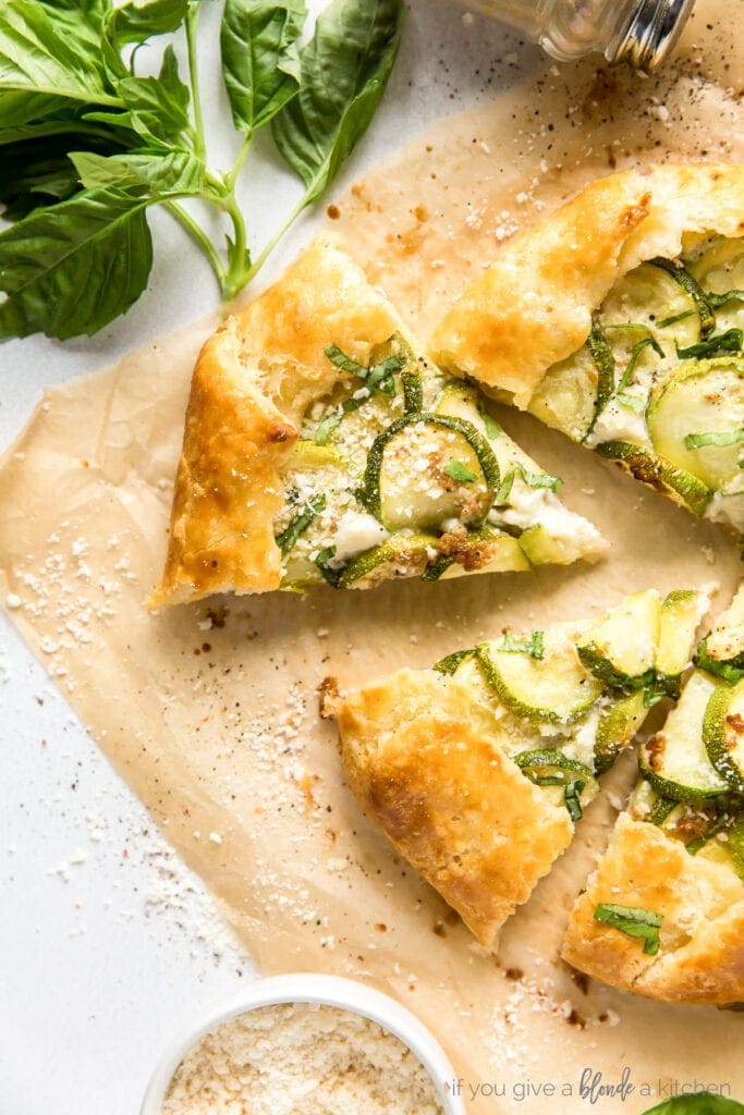 zucchini galette slices topped with grated parmesan on parchment paper