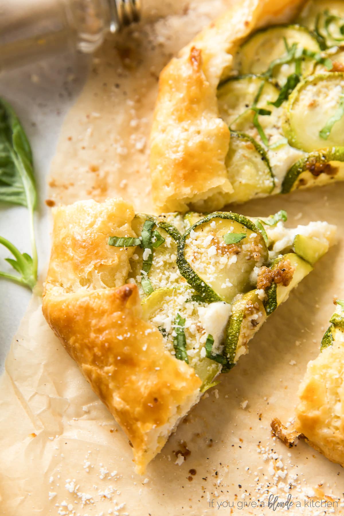 slice of zucchini galette topped with sprinkle of parmesan and fresh basil