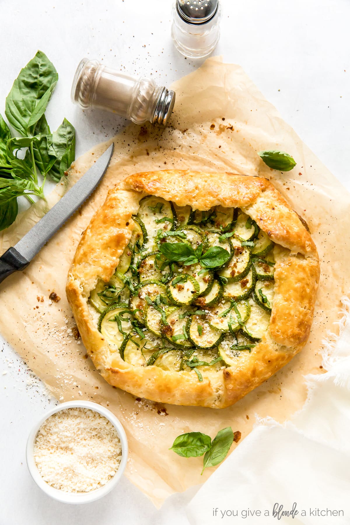 zucchini galette with golden crust topped with fresh basil on parchment paper