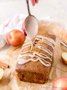 spoon drizzling glaze on top of apple cider bread