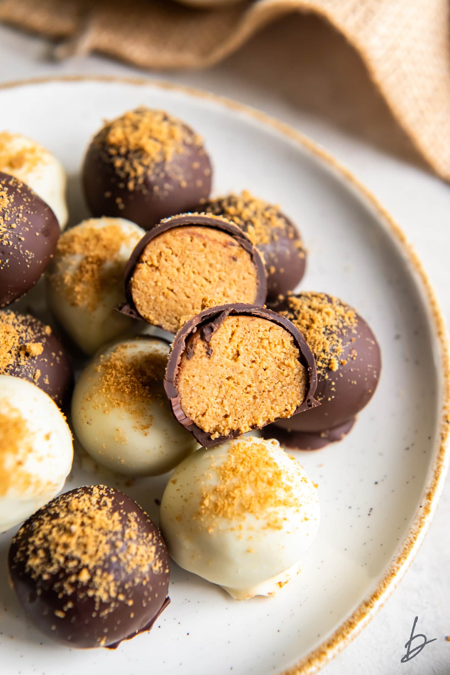 pumpkin truffle cut in half on top of other truffles on plate.