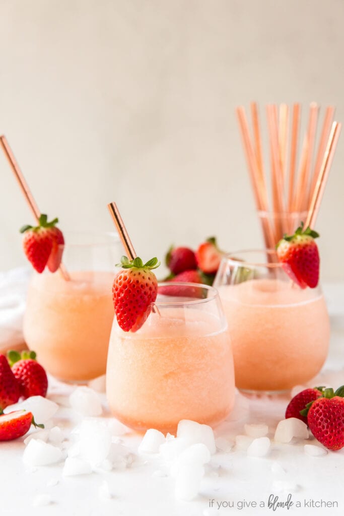 three stemless wine glasses filled with frozen rose and garnished with a strawberry