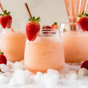 three frozen rose glasses with strawberries and stainless steel rose gold straws