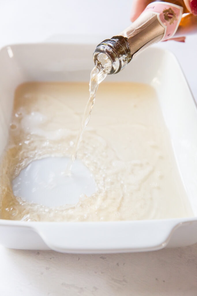 rosé being poured into a white ceramic 9x13 baking dish