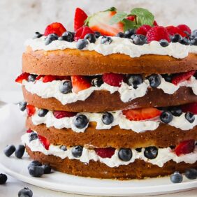 triple berry layer cake with exposed layers and summer berries