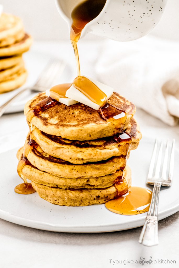 maple syrup poured on stack of pumpkin pancakes