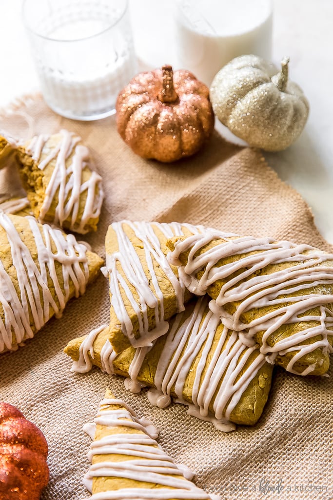 pumpkin scones drizzled with spiced glaze stacked on top of each other on burlap