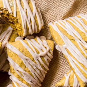 pumpkin scones with spiced glaze drizzle stacked on on burlap