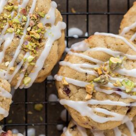 cranberry pistachio cookies with icing drizzled on top and chopped pistachios sprinkled on cookies