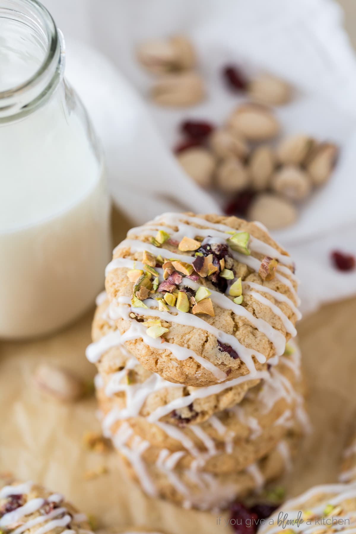 stack of cranberry pistachio cookies. top cookie with icing and chopped pistachios sprinkled on top