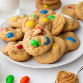 plate of peanut m&m cookies with m&ms and more cookies scattered around plate