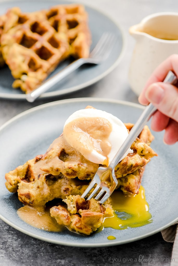 hand holding fork taking bite of leftover stuffing waffles with poached egg and gravy