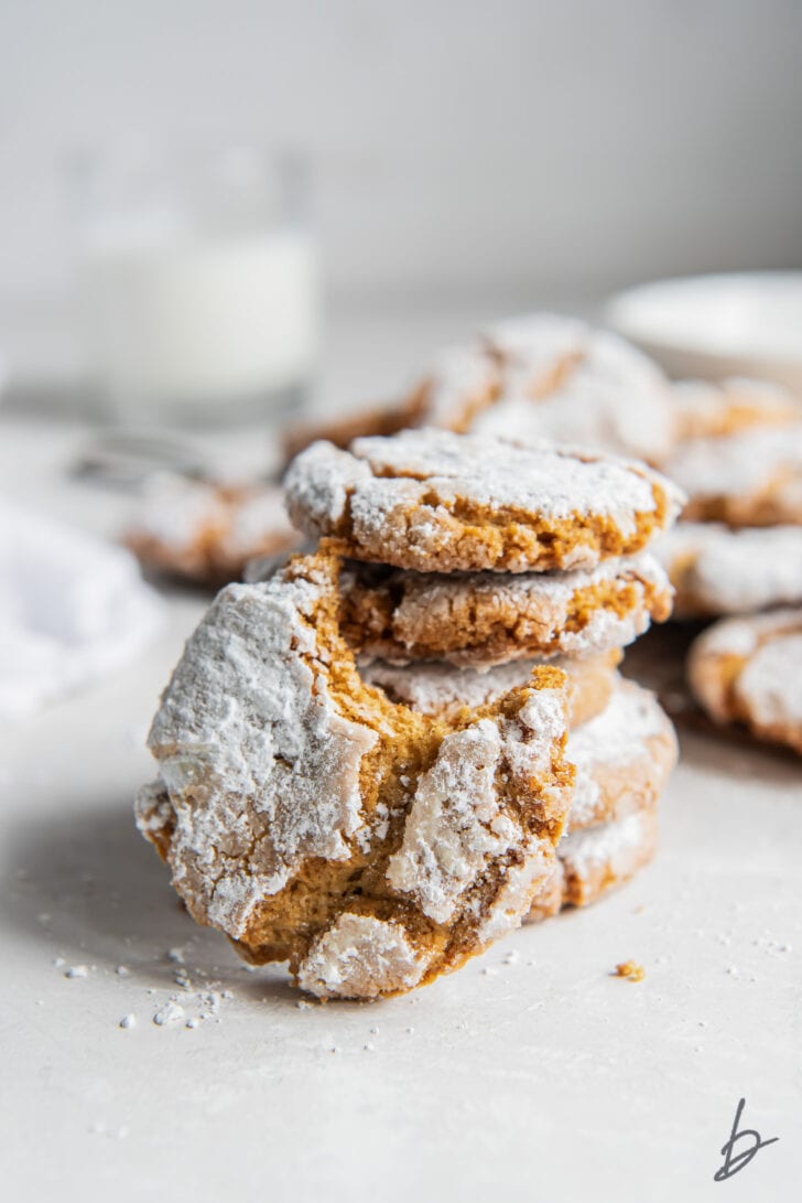 peanut butter crinkle cookie with a bite leaning on stack of cookies