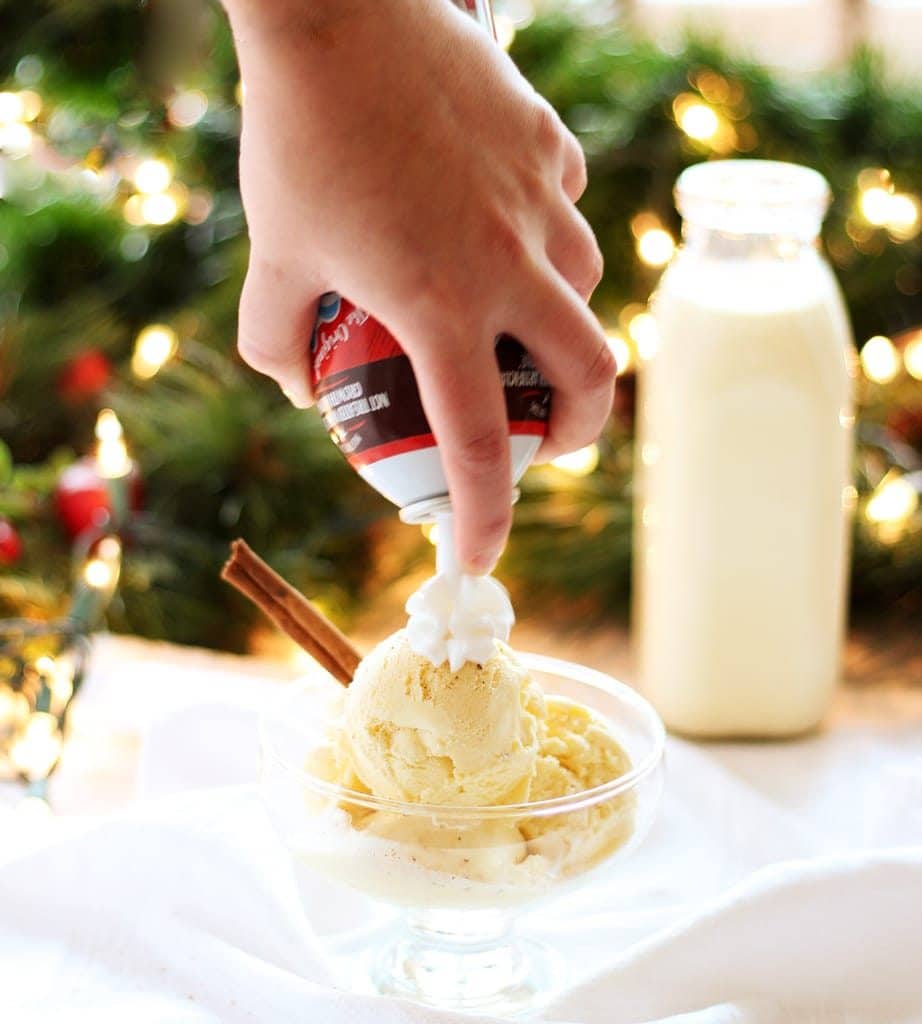 eggnog ice cream in dish and hand serving whipped cream from can