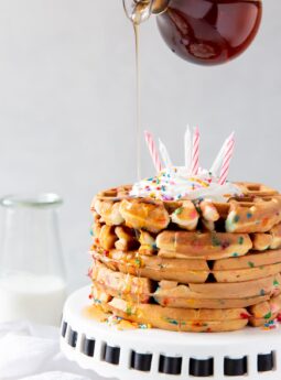 maple syrup being poured on stack of birthday cake mix waffles