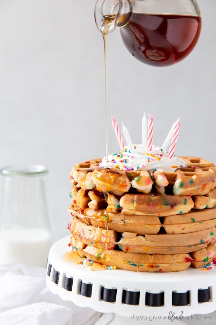 maple syrup being poured on stack of birthday cake mix waffles