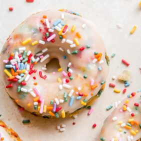 baked birthday donuts topped with glaze and rainbow sprinkles