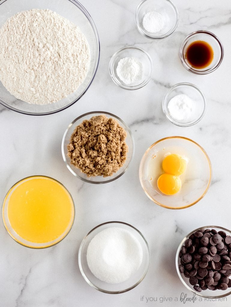 bowls of chocolate chip cookie ingredients flour, baking soda, cornstarch, salt, vanilla, brown sugar, eggs, melted butter, granulated sugar, chocolate chips