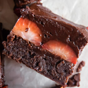 chocolate covered strawberry brownie on its side showing layers of brownie, strawberries and ganache