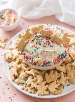 bowl of funfetti cake dip with animal crackers standing up in dip and surrounding bowl