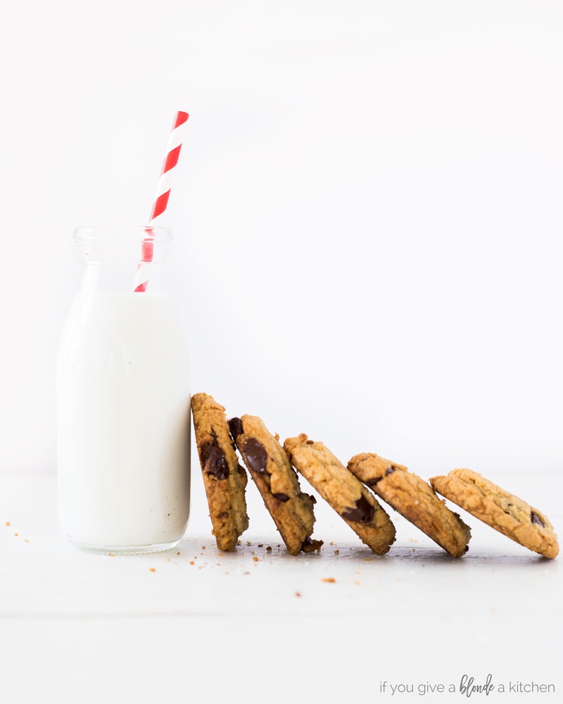 homemade chocolate chip cookies lined up next to each other next to glass of milk