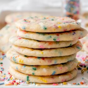 stack of seven sprinkle sugar cookies on baking sheet