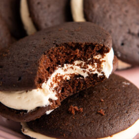 baileys chocolate whoopie pie with a bite on top of other whoopie pies on pink platter