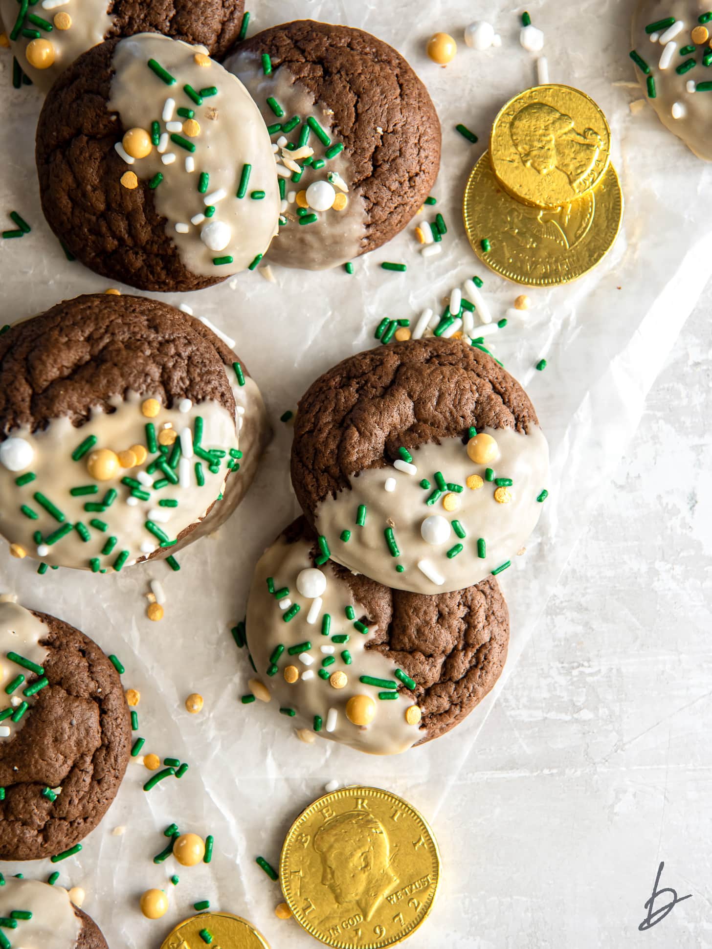 bailey's irish cream cookies with icing and sprinkles on parchment paper with some gold coins.