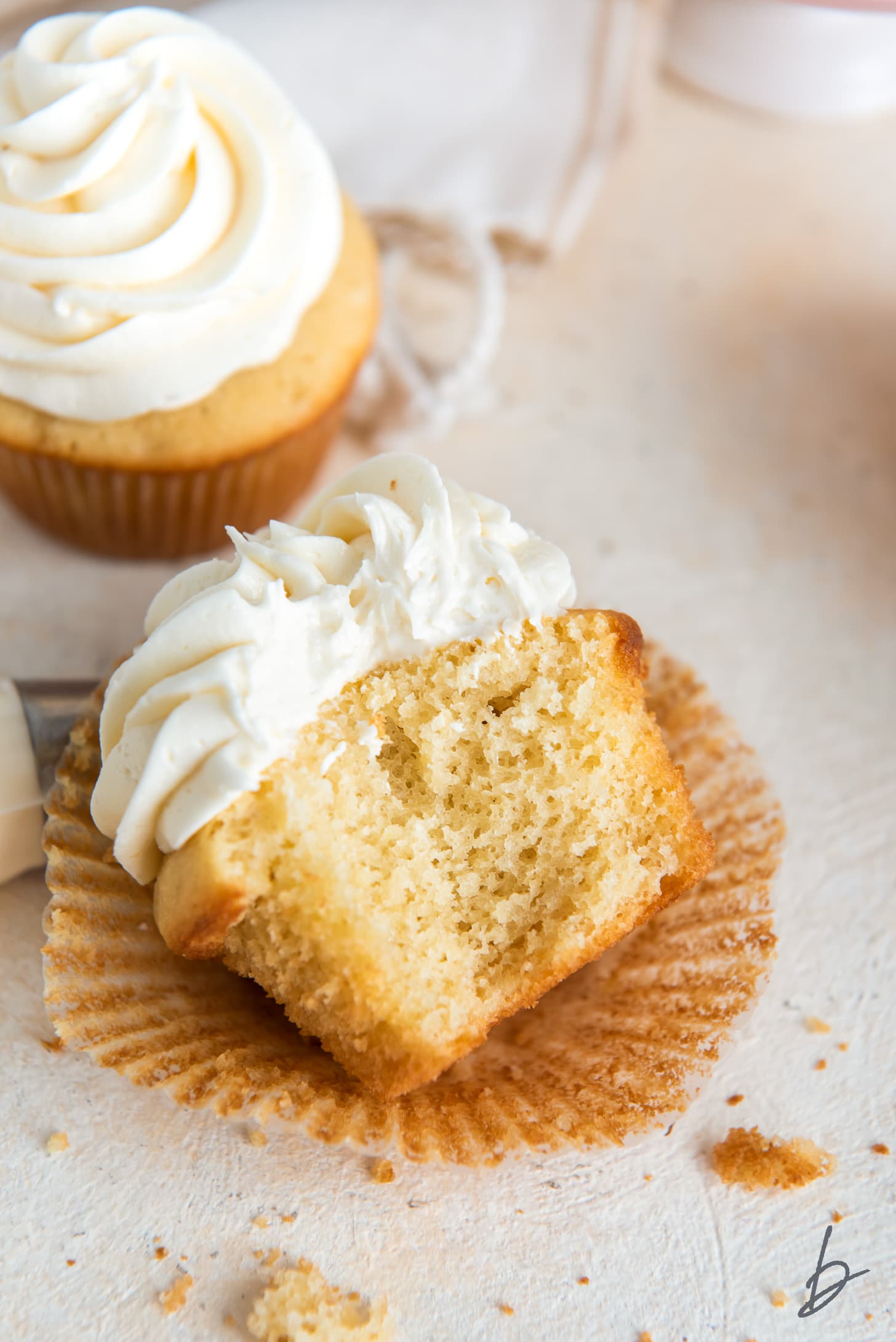 bite out of vanilla cupcake with buttercream frosting on paper cupcake liner