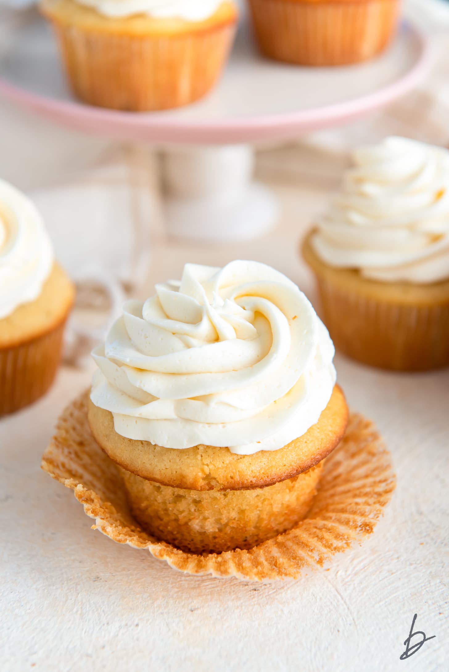 vanilla cupcake with buttercream frosting on unfolded cupcake liner