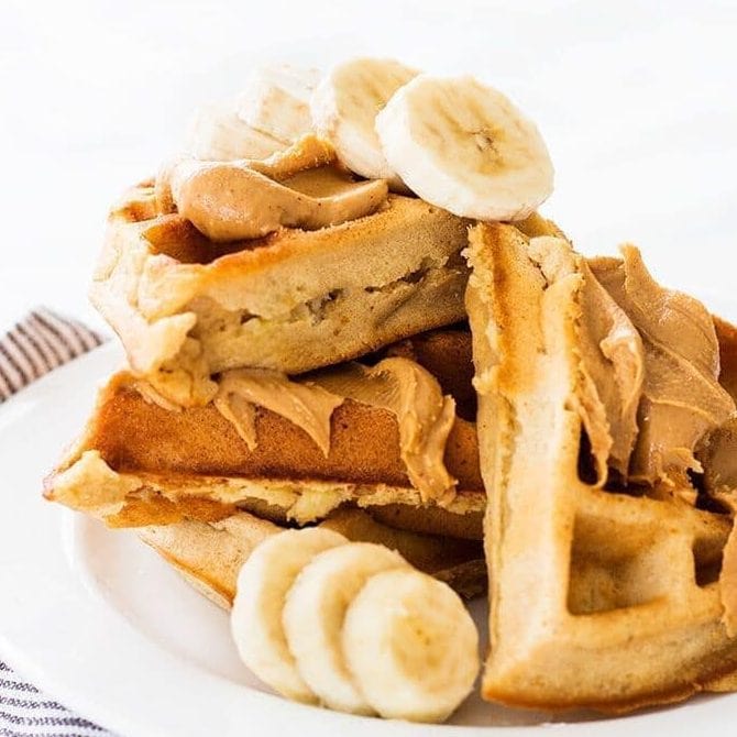 stack of waffles with peanut butter spread on top and slices of banana