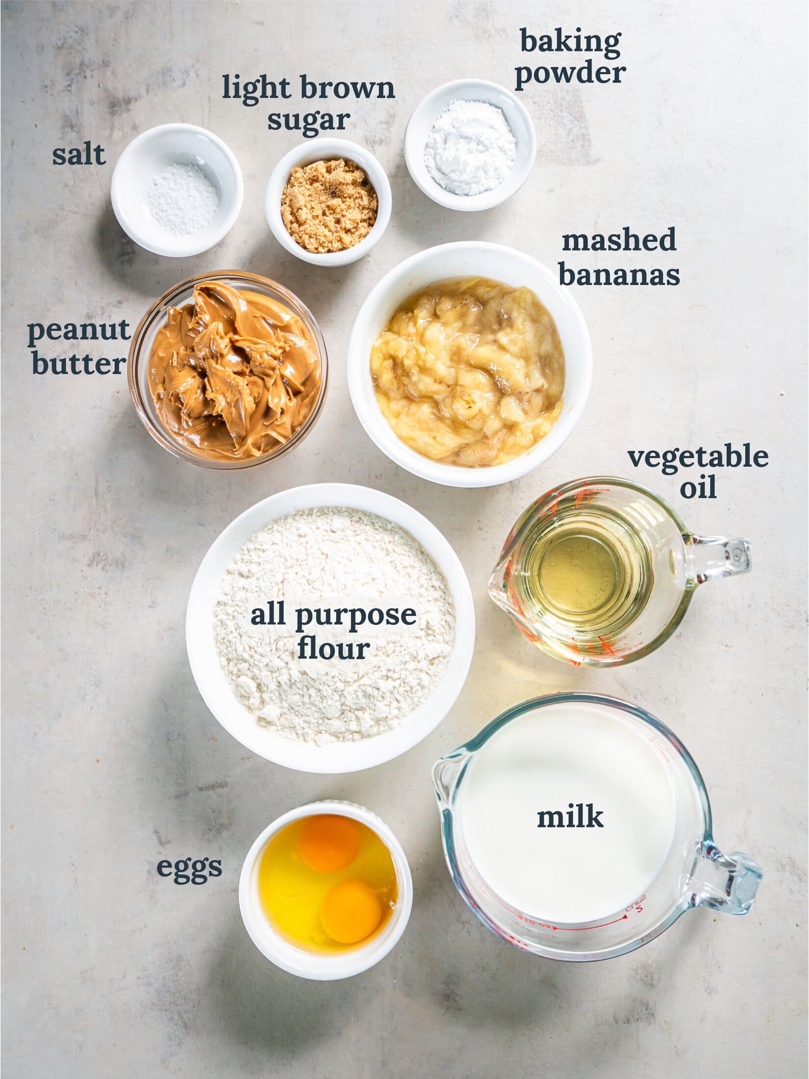 Tabletop with bowls of ingredients to make peanut butter banana waffles.