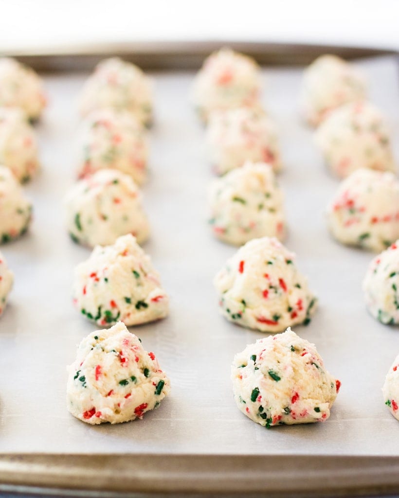 balls of edible cookie dough on parchment lined cookie sheet