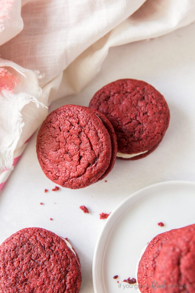 red velvet sandwich cookies on a surface with one cookie leaning on another cookie