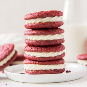 stack of four red velvet sandwich cookies with cream cheese frosting