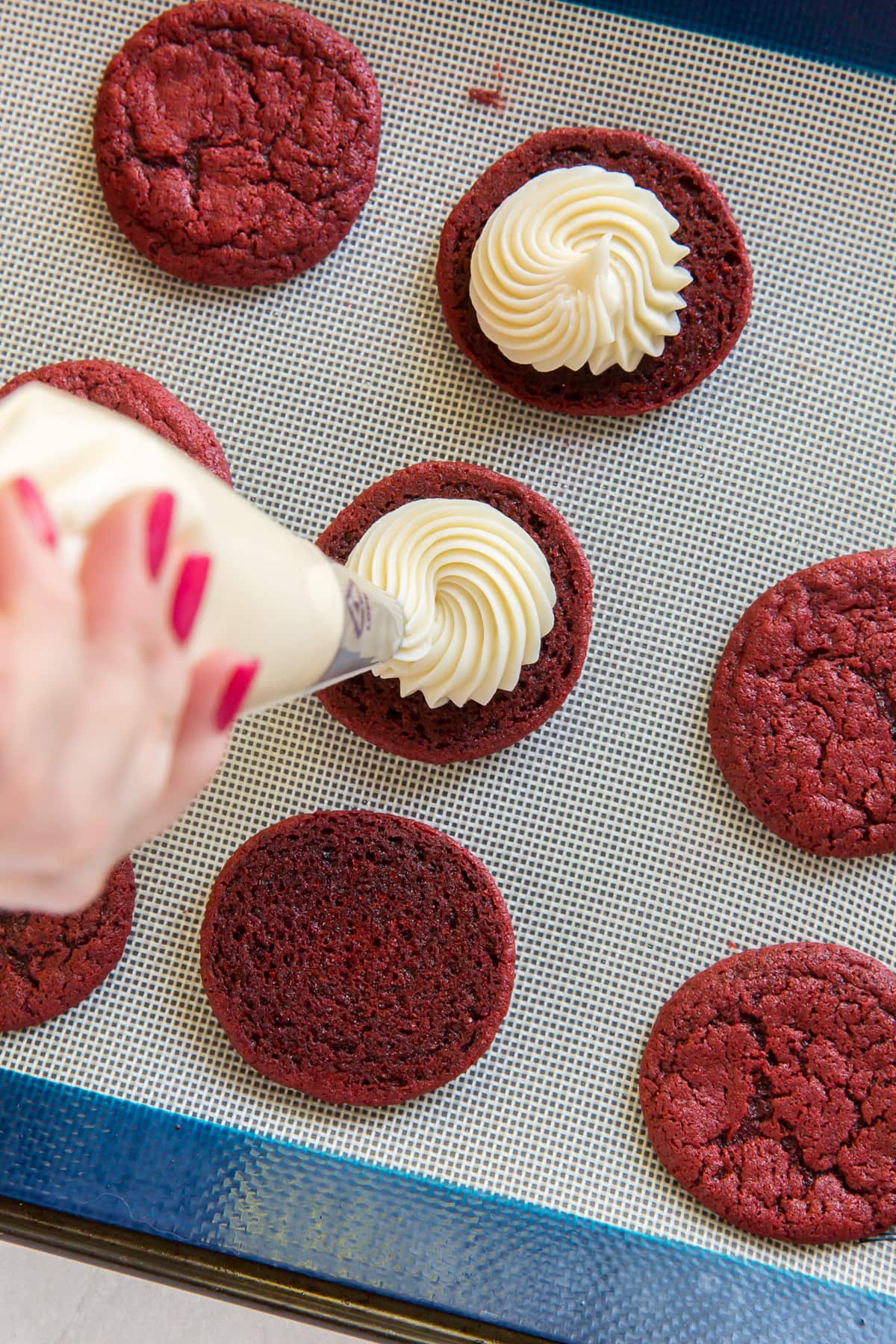 The cream cheese frosting inside these red velvet sandwich cookies is amazing. The recipe is easy to follow too! | www.ifyougiveablondeakitchen.com