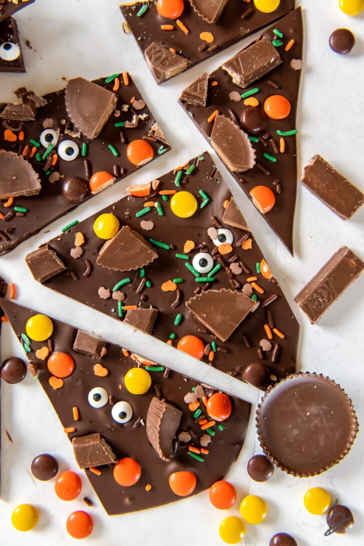 pieces of broken halloween candy bark surrounded by Reese's piece and peanut butter cups